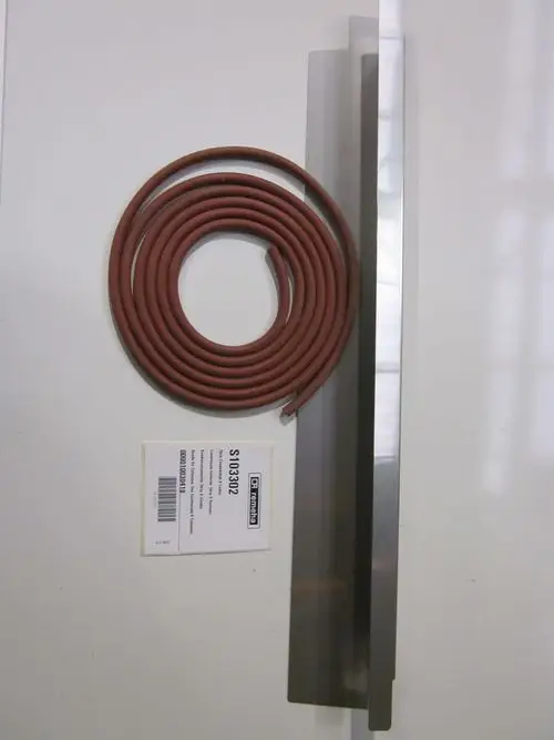 Kondensatsammler mit einer roten Dichtungsschnur und zwei Blechplatten. Das Produkt gehört zur Marke Remeha. Im Hintergrund ist ein Etikett mit Artikelnummer sichtbar.